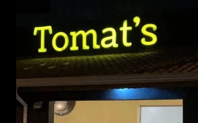 Letra caixa Tomat's com iluminação frontal LED amarela em fachada noturna