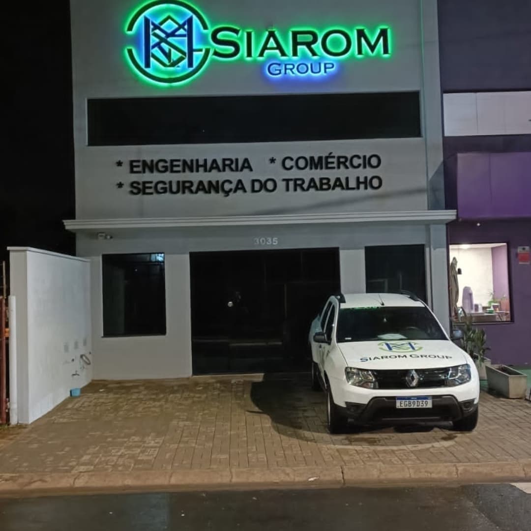 Fachada do Siarom Group com letra caixa luminosa em verde e azul sobre fachada cinza